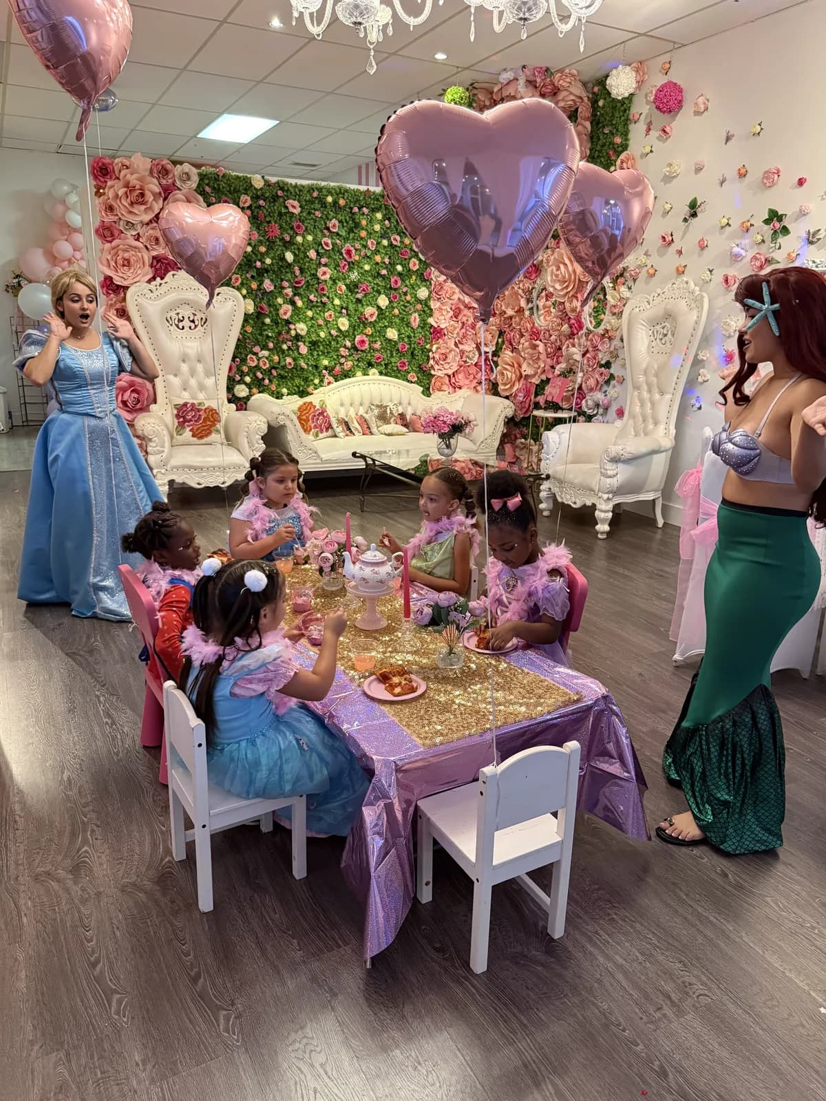 Cinderella and Ariel with birthday party girls at gold sequin table in South Florida princess spa